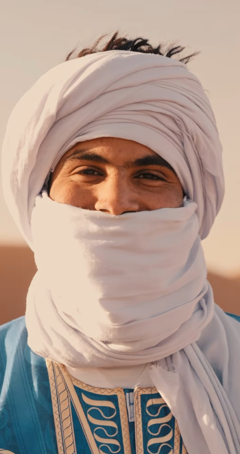 Madi, desert driver and route specialist, wearing a white turban and blue robe.
