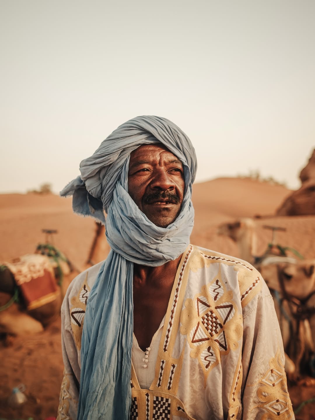 Salem, desert cook and cultural host, wearing a pale turban and embroidered robe.
