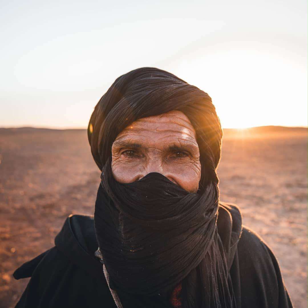 Uncle Laaribi, camel guide, photographed in a black turban in the Sahara light.